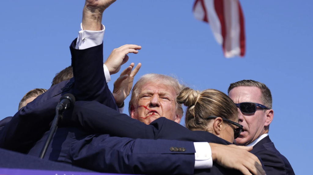 Trump raises his fist, his face covered in blood. (AP)
