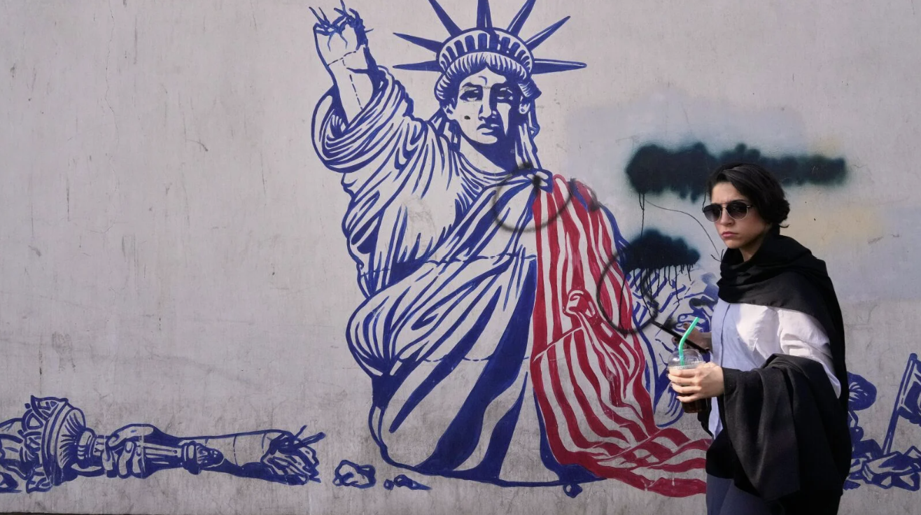 A woman walks past an anti-American mural on the wall of the former U.S. embassy, ​​now a museum, in Tehran. AP Photo/Vahid Salemi